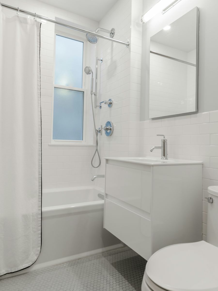 Stock photo of a different, spotless white bathroom with a tub, vanity, and tile floor