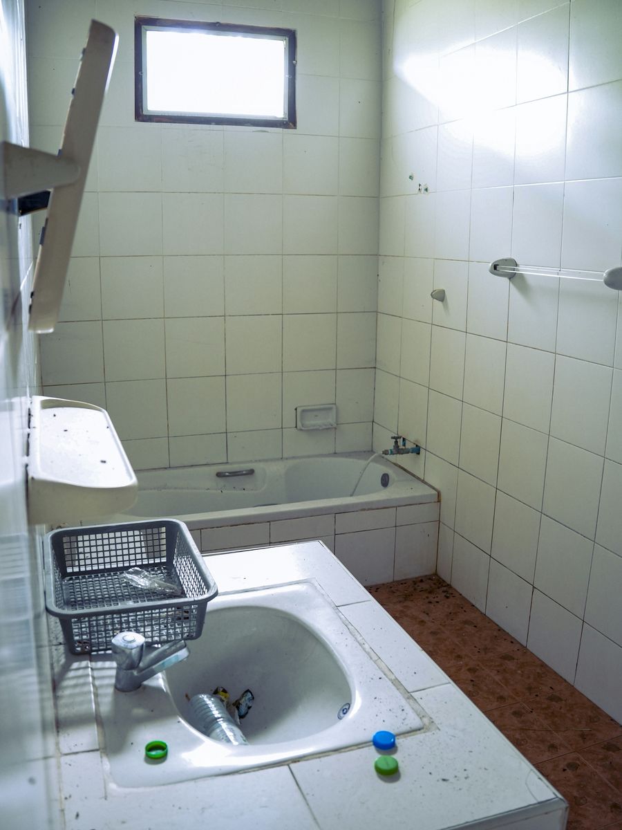 Stock photo of a grimy tiled bathroom with a cluttered sink and dirt on the floor