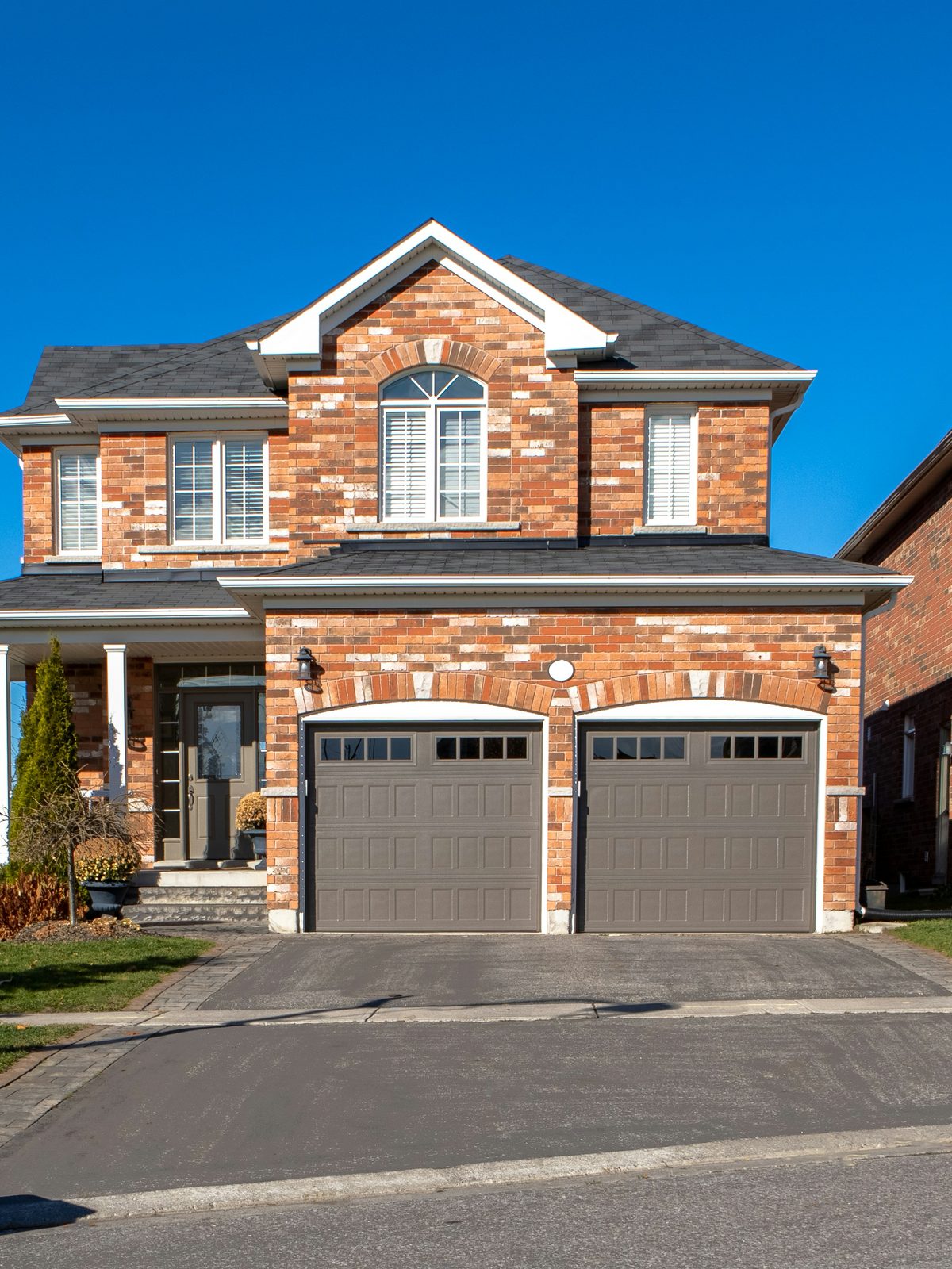 Two-story brick house with a two-car garage and a smooth dark asphalt driveway